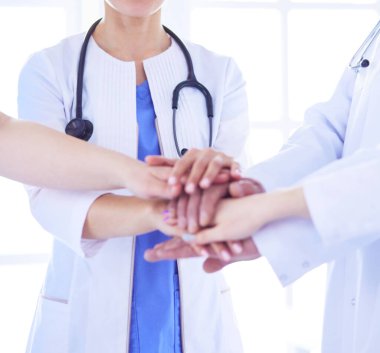 Bir grup doktor ellerini birleştiriyor. Yakın plan.