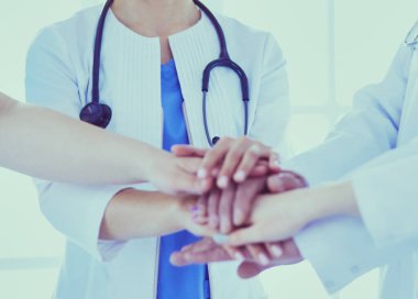 Bir grup doktor ellerini birleştiriyor. Yakın plan.