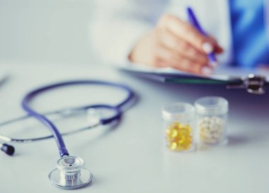 Elinde bir kutu beyaz hap ve masada yazılı tedavi planı tutan bir kadın.