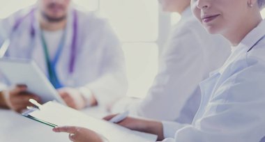 Ciddi bir tıbbi ekip parlak bir ofiste dizüstü bilgisayar kullanıyor.
