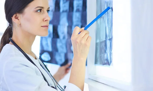 Giovane medico femminile sorridente con stetoscopio che punta ai raggi X presso lo studio medico — Foto Stock