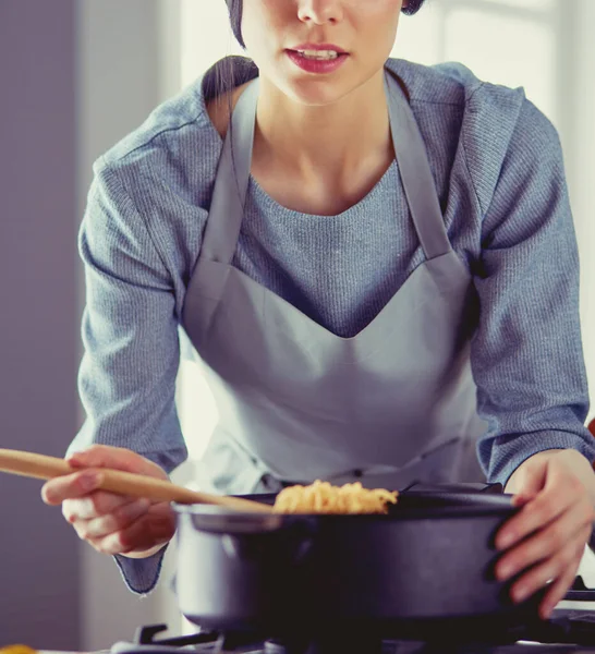 Женщина, стоящая у плиты на кухне, готовит и нюхает приятные ароматы  . — стоковое фото