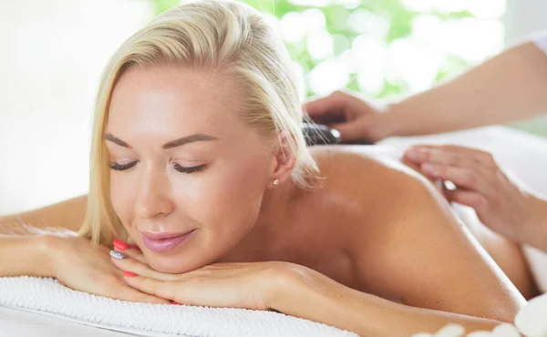 Menina jovem e bonita relaxante no salão de spa. Terapia de massagem durante o verão sazonal ou fundo de primavera — Fotografia de Stock