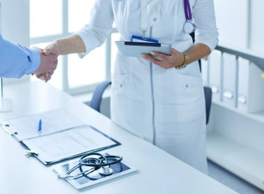 Yaşlı bir çiftle el sıkışan kadın doktor.
