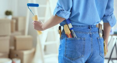 Güzel bir kadın evin iç duvarını boya ile boyuyor.