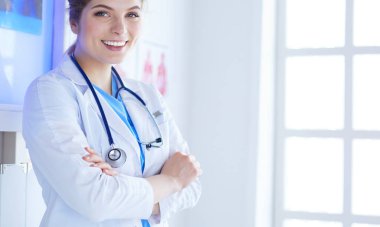 Beyaz üniformalı genç kadın doktor klinikte bekliyor.