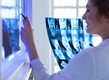 Genç, profesyonel kadın doktor hastaların röntgenlerini çekiyor.