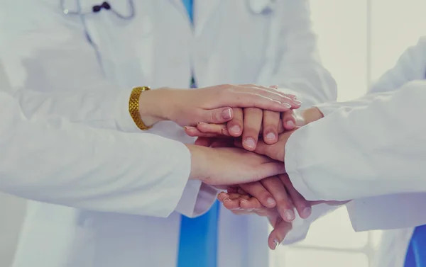 Médicos e enfermeiras a empilhar as mãos. Isolado em branco — Fotografia de Stock