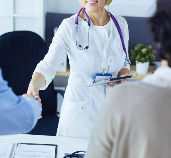 Woman doctor handshaking with a senior couple