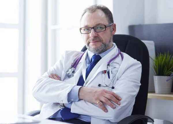 Retrato del médico senior en el consultorio sentado en el escritorio — Foto de Stock