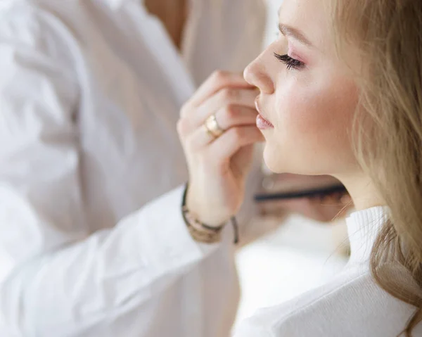 Make up artist gör professionell make up av ung kvinna — Stockfoto