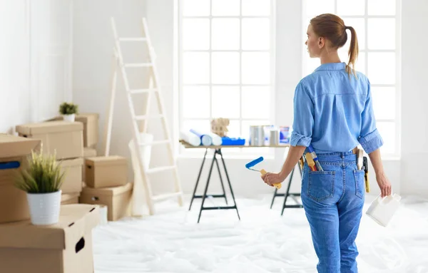 Ganska smilling kvinna målning interiör vägg i hemmet med färg roller — Stockfoto