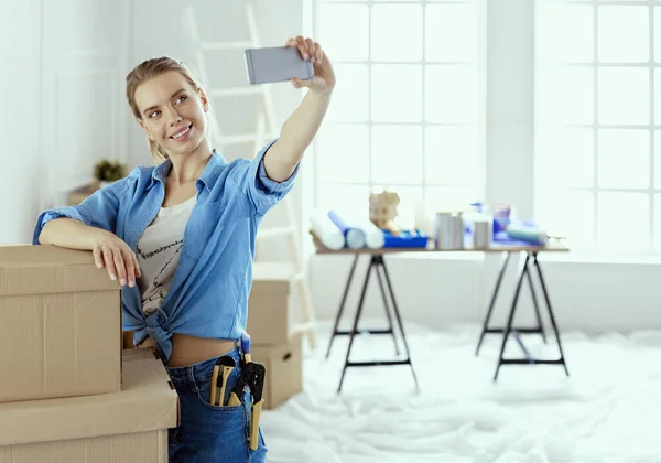 Счастливая молодая женщина делает селфи, весело улыбаясь, переехав в новую квартиру — стоковое фото
