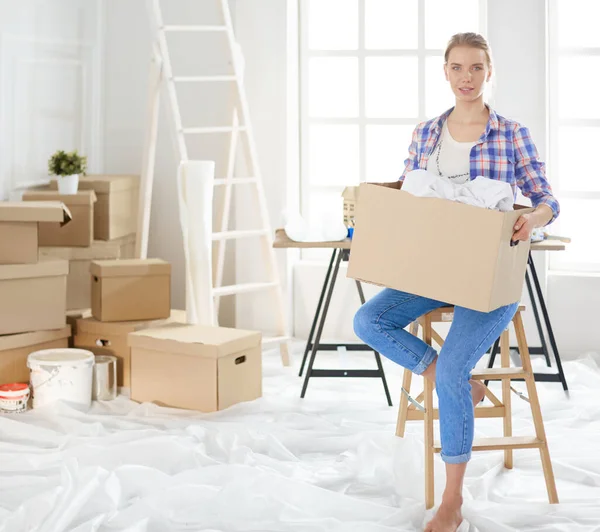 Een mooie alleenstaande jonge vrouw uitpakken dozen en verhuizen naar een nieuw huis — Stockfoto