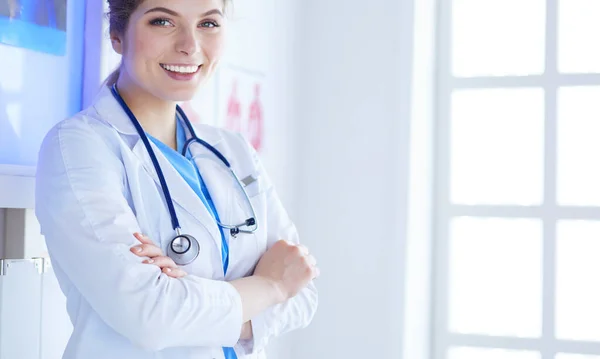 Mujer joven médica en uniforme blanco de pie en la oficina de clínicas —  Fotos de Stock