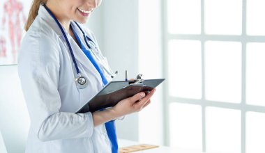 Kadın doktor hastanede dosyayla bekliyor.