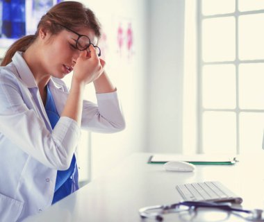 İş yerinde baş ağrısı çeken genç bir kadın doktorun portresi.