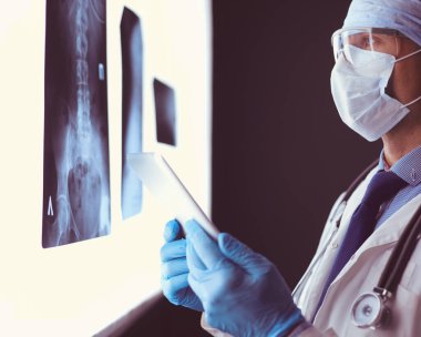 Genç doktor, izole edilmiş beyaz arka planda röntgen görüntüsü arıyor.