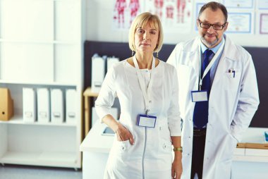 Ciddi bir tıbbi ekip parlak bir ofiste dizüstü bilgisayar kullanıyor.