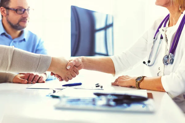 Woman doctor handshaking with a senior couple