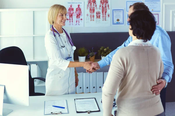 Female doctor handshaking a patients hand and smiling