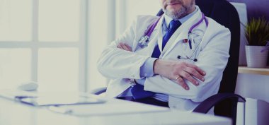 Masada oturan kıdemli doktorun portresi.