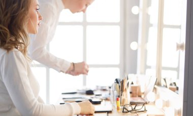 Makyöz, genç bir kadının profesyonel makyajını yapıyor.