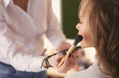 Genç ve güzel gelin, profesyonel makyözün düğün makyajını yapıyor.