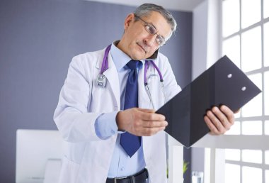 Erkek doktor hastanedeki panoya notlar yazıyor.