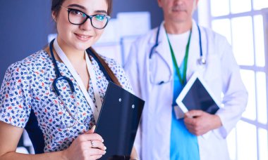 Bir doktor ekibi, kadın ve erkek, ofiste bekliyorlar.