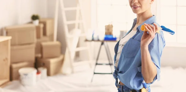 Mooie glimlachende vrouw schilderen interieur muur van huis met verfroller — Stockfoto