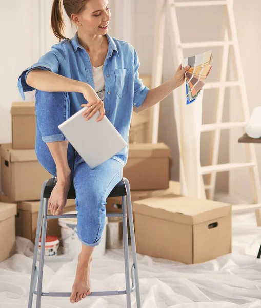 Jonge vrouw zit thuis en koopt nieuwe meubels via internet met behulp van een tablet computer — Stockfoto