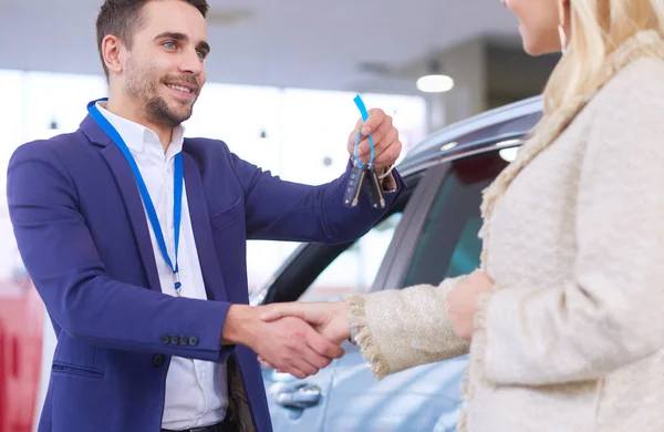 Car salesman sells a car to happy customer in car dealership and hands over the keys. — Stock Photo, Image