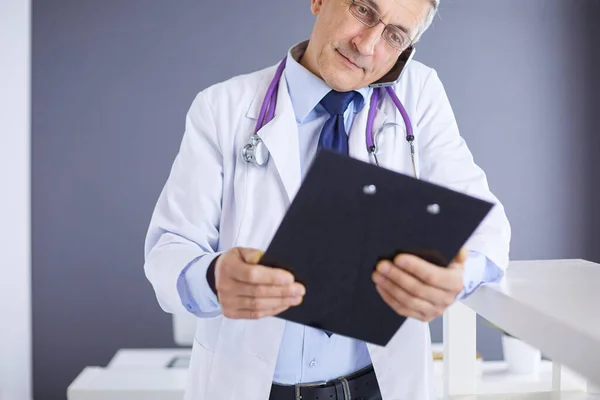 Мужчина-врач пишет заметки на планшете в больнице — стоковое фото