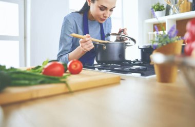 Mutfakta ahşap kaşıkla yemek pişiren kadın