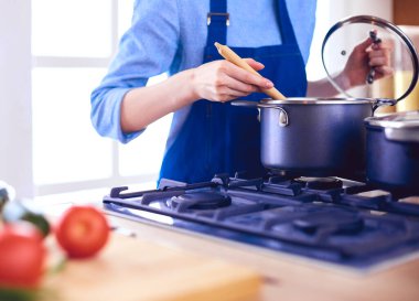 Mutfakta ahşap kaşıkla yemek pişiren kadın