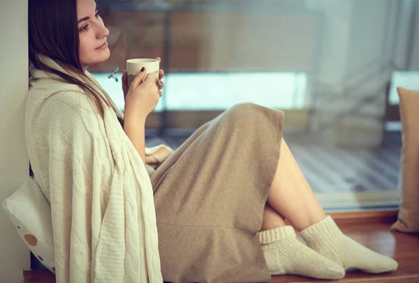 beautiful woman drinking coffee in the morning sitting by the window