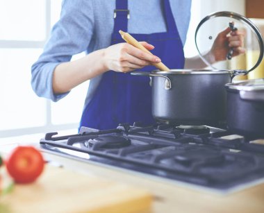 Mutfakta ahşap kaşıkla yemek pişiren kadın