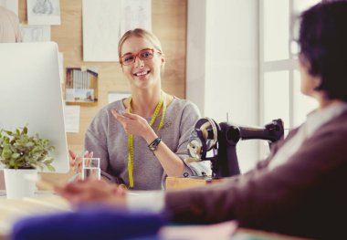 Kadın terzi, dikiş atölyesindeki özel dikim elbise hakkında potansiyel müşteriyle iletişim kuruyor.