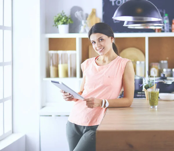 Bela jovem mulher usando um tablet digital na cozinha — Fotografia de Stock