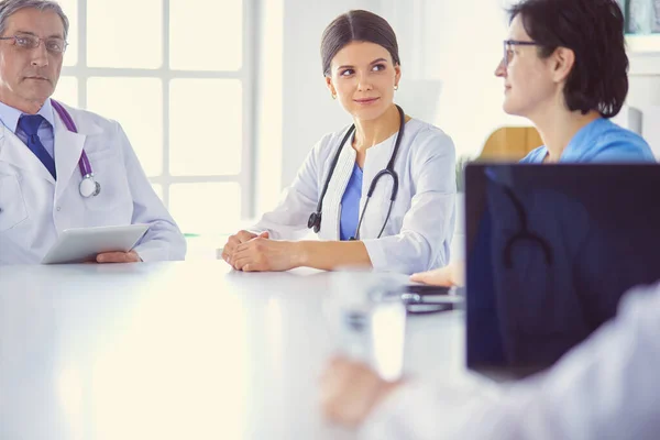 Equipo médico serio discutiendo casos de pacientes en un consultorio luminoso —  Fotos de Stock