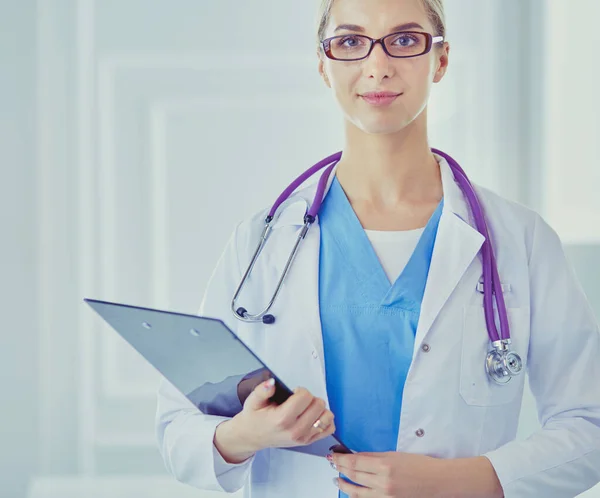 Médico sonriente con una carpeta en uniforme de pie —  Fotos de Stock