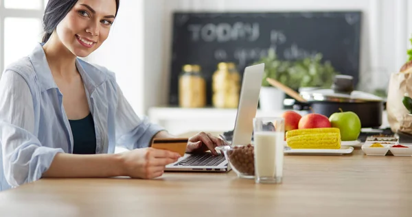 Donna sorridente shopping online con tablet e carta di credito in cucina — Foto Stock