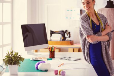 Güzel moda tasarımcısı stüdyoda duruyor.