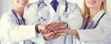 Doktorlar ve hemşireler tıbbi bir ekipte el ele tutuşuyorlar.