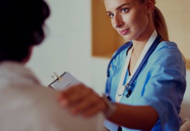 Kadın doktor yaşlılara hastanede el ele tutuşmalarında yardım ediyor