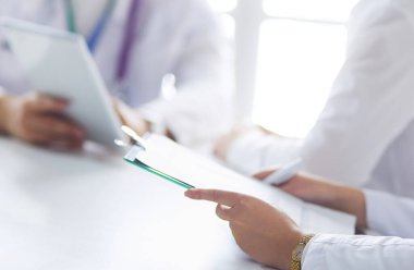 Ciddi bir tıbbi ekip parlak bir ofiste dizüstü bilgisayar kullanıyor.