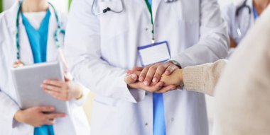 Doktorlar ve hemşireler tıbbi bir ekipte el ele tutuşuyorlar.