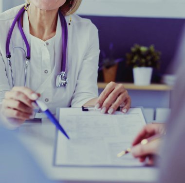 Doktor ve hasta tıbbi kayıtları olan bir dosyayı inceliyor. Tekerlekli sandalyede oturuyor.