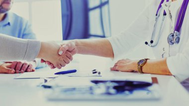 Yaşlı bir çiftle el sıkışan kadın doktor.